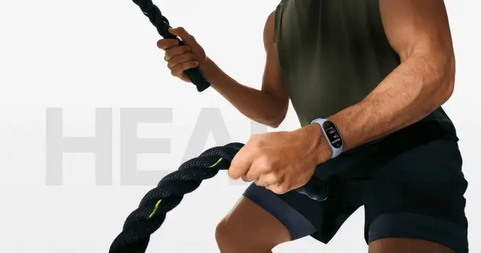 Egy férfi látható edzés közben, amint vastag edzőköteleket (battle rope) használ, csuklóján egy világoskék szíjas Xiaomi Smart Band 9 aktivitásmérővel, a háttérben pedig elmosódott „HEALTH” felirat látszik.
