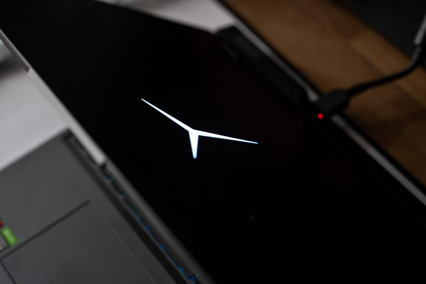 Lenovo Legion laptop sötét képernyője, közepén a fehéren világító, háromágú Y alakú Legion márkajelzéssel.