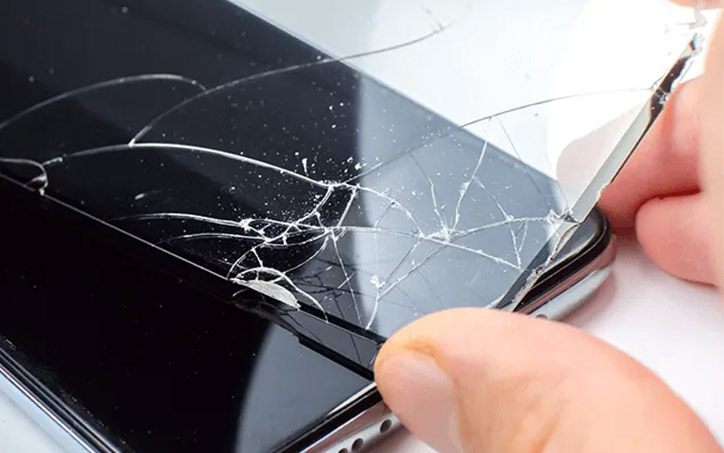 Egy okos telefon aminek épp a betört kijelzőjét cseréli egy kéz. 