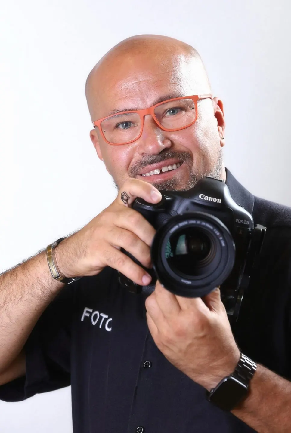 Mekli Zoltán egy Canon EOS-1D fényképezőgépet tart a kezében egy fehér háttér előtt.