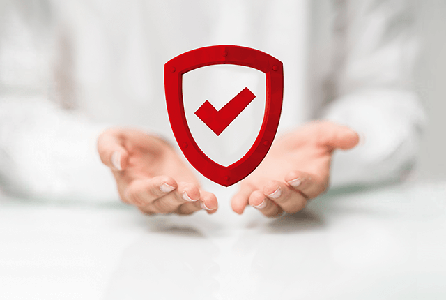 Két kéz tart egy piros pajzsot, amelyen egy pipa látható, fehér háttér előtt.