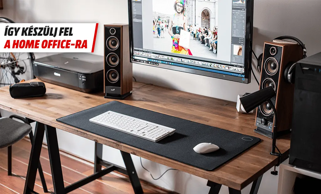 Modern home office sarok monitorral, hangfalakkal és billentyűzettel egy fa asztalon. Így készülj fel a home office-ra felirattal.