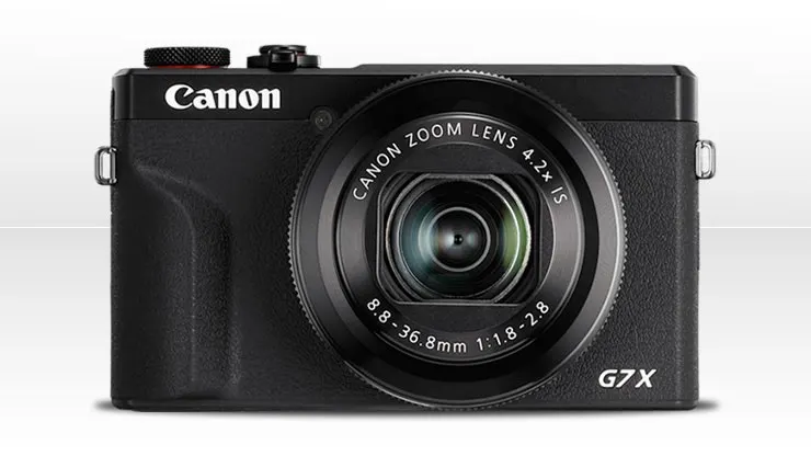 Egy kompakt kivitelű, fekete színű Canon PowerShot G7 X digitális fényképezőgép szemből nézve, zárt objektívvel.