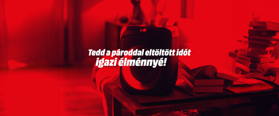 Vörös szín dominál, asztalon fekete tárgy, könyvek és felirat: "Tedd a pároddal eltöltött időt igazi élménnyé!".