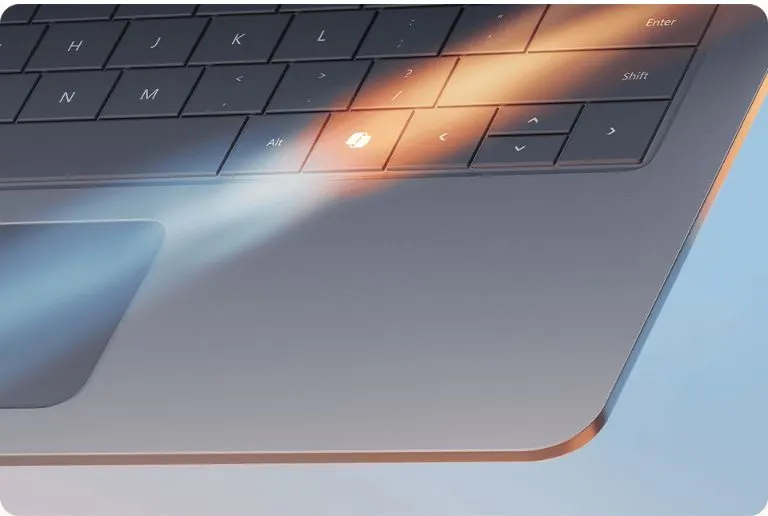 Szürke laptop részlete, billentyűzet és érintőpad látható, fény tükröződésekkel.