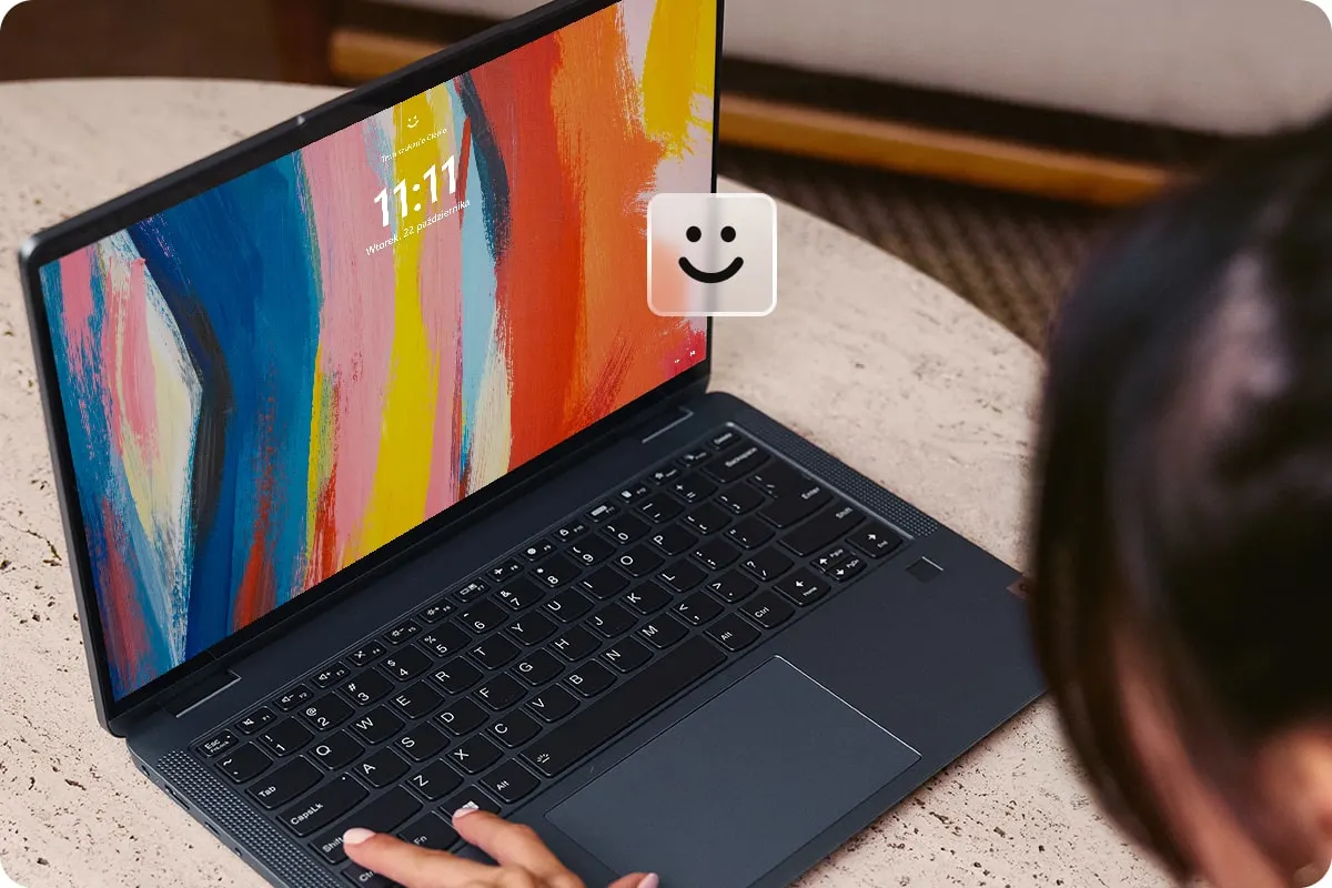 Fekete laptop látható színes kijelzővel, amin 11:11 látható. Egy kéz a billentyűzetet használja.