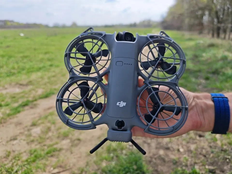 DJI Neo 2 kompakt drón felülnézete kézben tartva, propellervédőkkel.