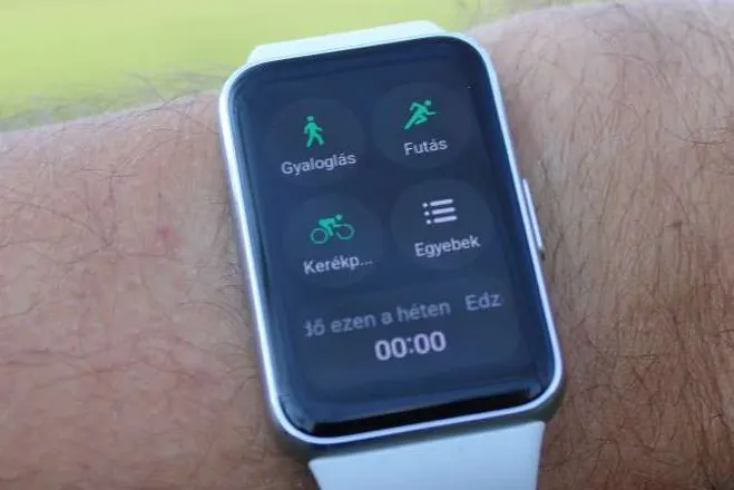 Közeli fotó egy csuklón lévő Huawei Watch Fit 3 okosóráról, amelynek kijelzőjén az edzés menü látható négy ikonnal (gyaloglás, futás, kerékpár, egyebek) és a heti edzésstatisztikával.