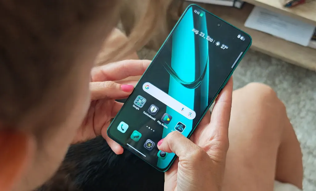 Realme GT 7 eszköz használat közben, egy kanapén ülő személy kezében