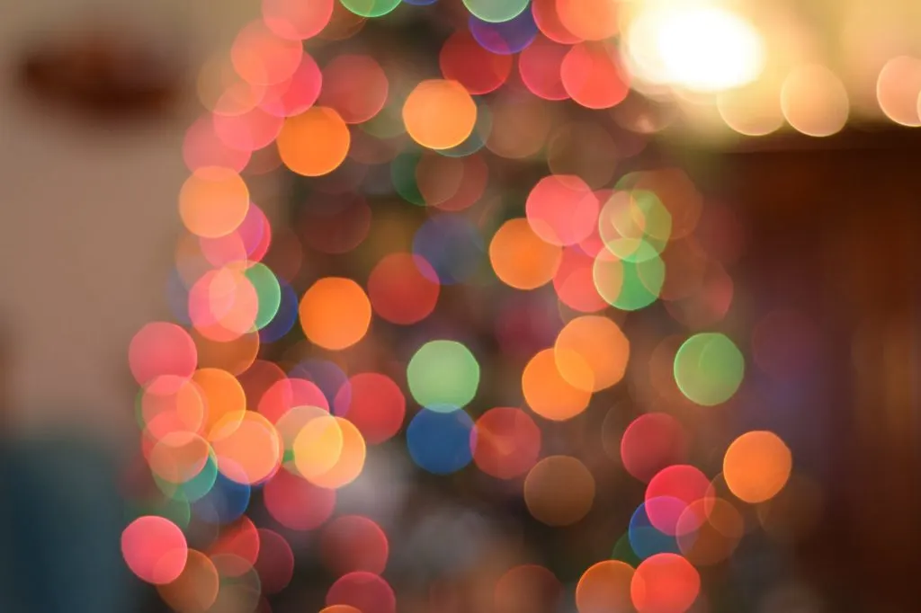 Karácsonyi fényfüzér elmosódott, lágy fényfoltjai (bokeh hatás) színes körökként (piros, sárga, zöld, kék) ragyognak a háttérben.