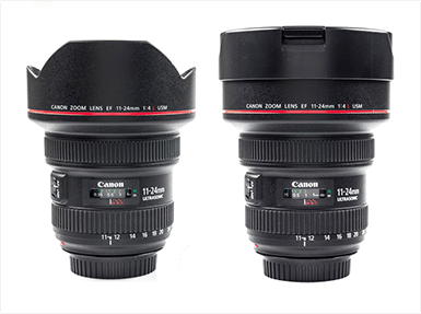 Két fekete Canon zoom objektív látható. A feliratok pirosak. Az objektívek fehér háttér előtt állnak.