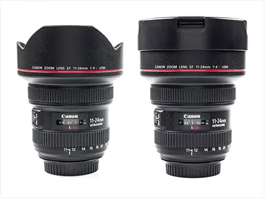 Két fekete Canon zoom objektív látható. A feliratok pirosak. Az objektívek fehér háttér előtt állnak.