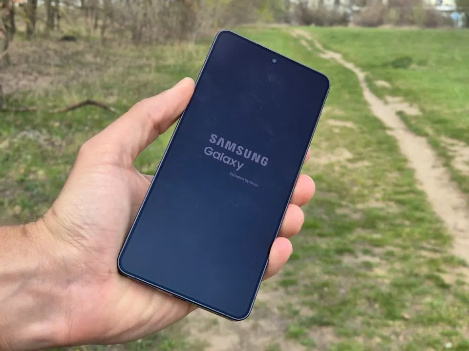 Samsung Galaxy S24 Ultra okostelefon bekapcsolási képernyője kézben tartva a szabadban.