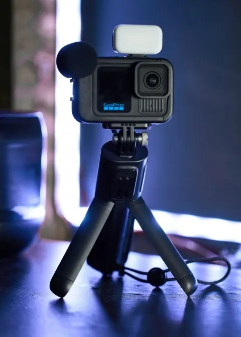 GoPro HERO13 Black Creator Edition összeállítás: az akciókamera Media Mod keretben, külső mikrofonnal és LED lámpával felszerelve, egy asztalon álló tripodra rögzítve.