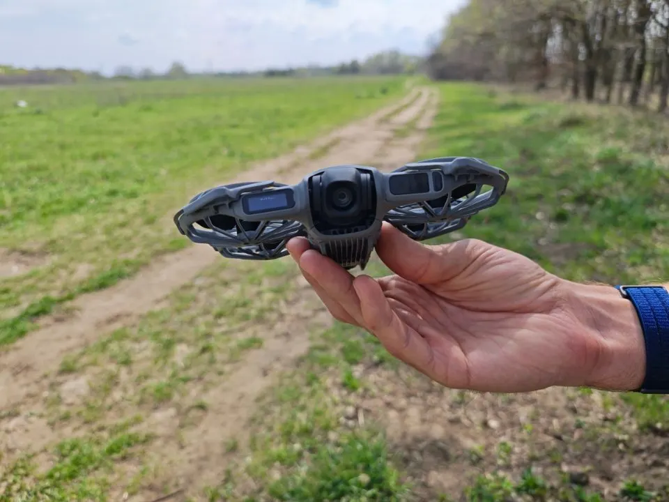 DJI Neo 2 drón elölnézete kézben tartva, jól látható kamerával és védőkerettel.