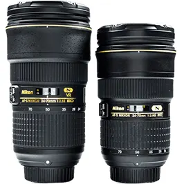 Két fekete Nikon fényképezőgép objektív látható, feliratokkal és arany díszítéssel, fehér háttér előtt.