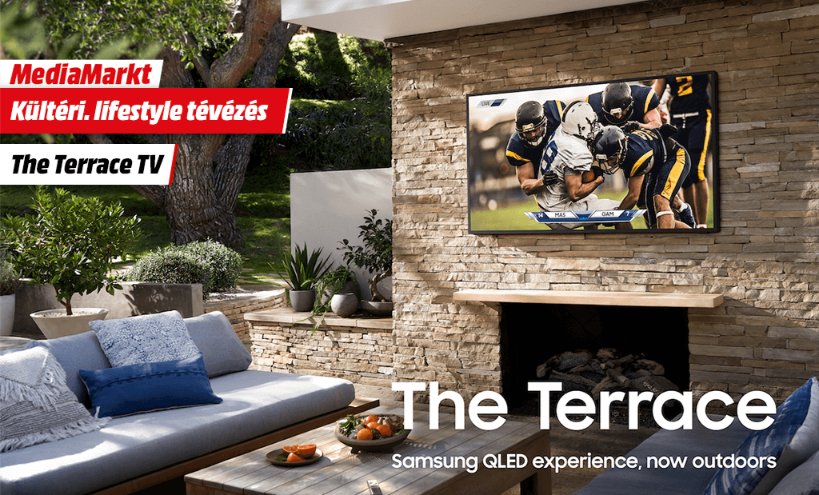 Samsung The Terrace kültéri QLED TV MediaMarkt promóció kőfalra szerelve egy elegáns, kerti bútorokkal berendezett teraszon.
