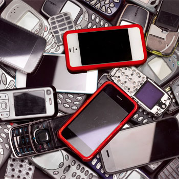 Különböző mobiltelefonok halmaza, köztük okostelefonok piros kerettel és régebbi modellek gombokkal.