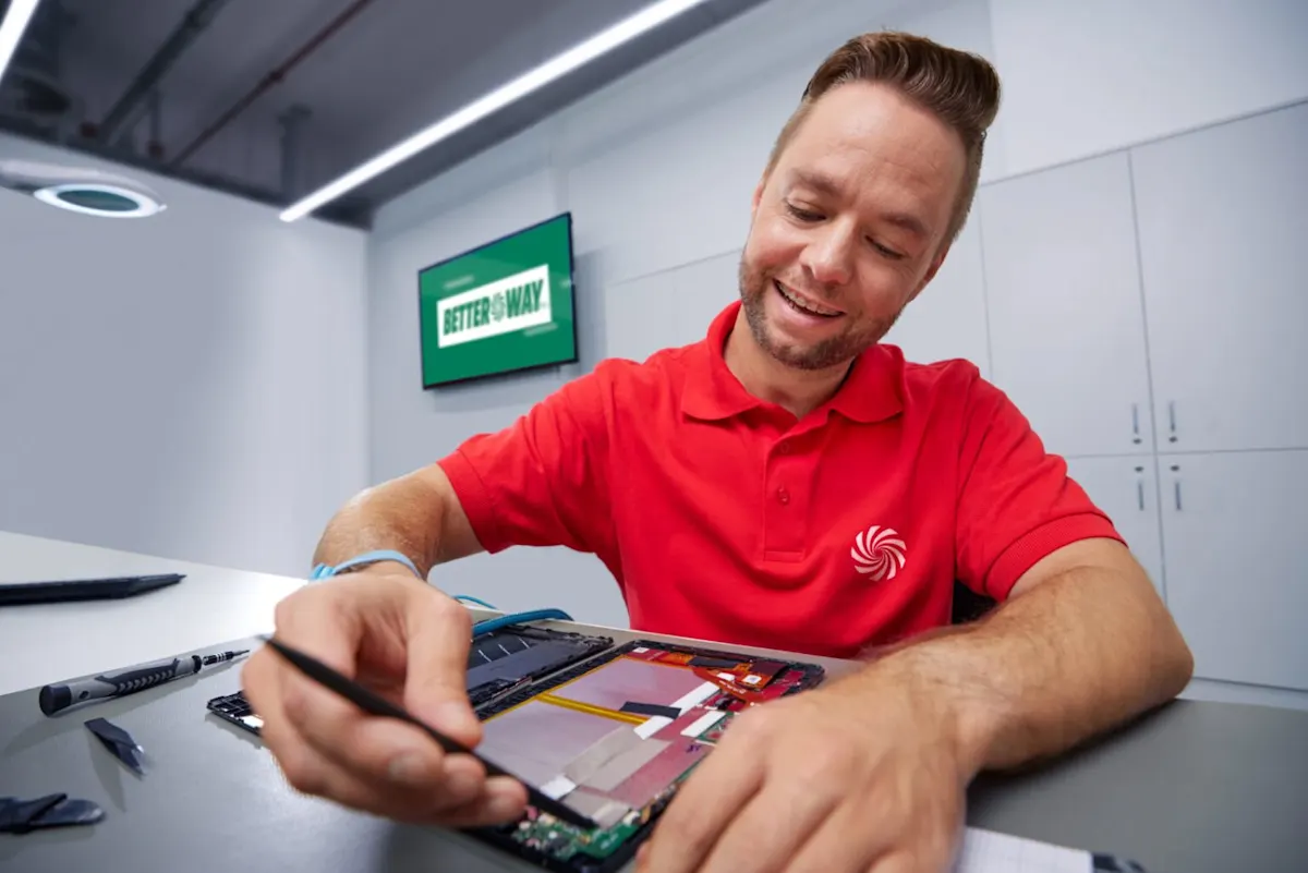 MediaMarkt szervizes szakember egy tabletet javít munka közben, háttérben a BetterWay logóval.