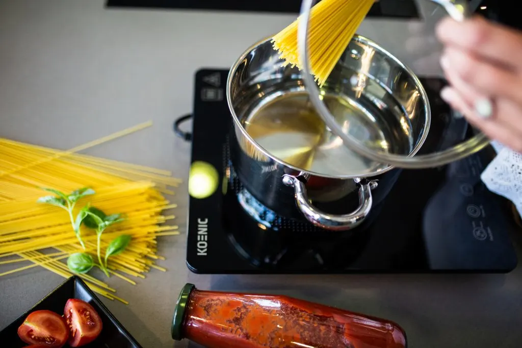 Spagetti tészta főzése egy KOENIC hordozható indukciós főzőlapon elhelyezett rozsdamentes edényben, paradicsomszósszal.