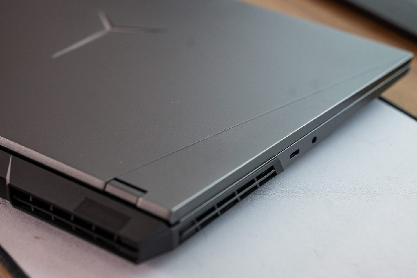 Közeli kép egy Lenovo Legion laptop sötétszürke fedlapjáról, az oldalsó szellőzőnyílásról és egy USB-C portról.