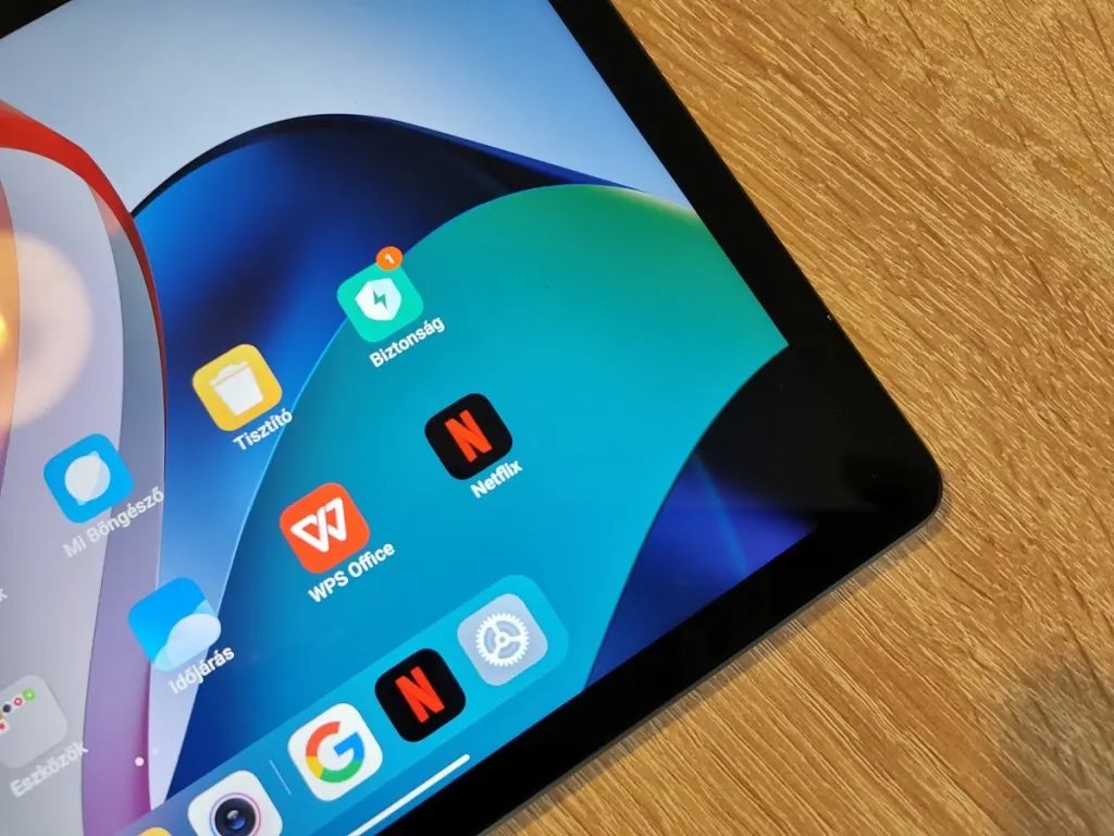 Közeli fotó egy táblagép kijelzőjéről, rajta a Biztonság, Netflix, WPS Office és Mi Böngésző alkalmazások ikonjaival, fa felületen.
