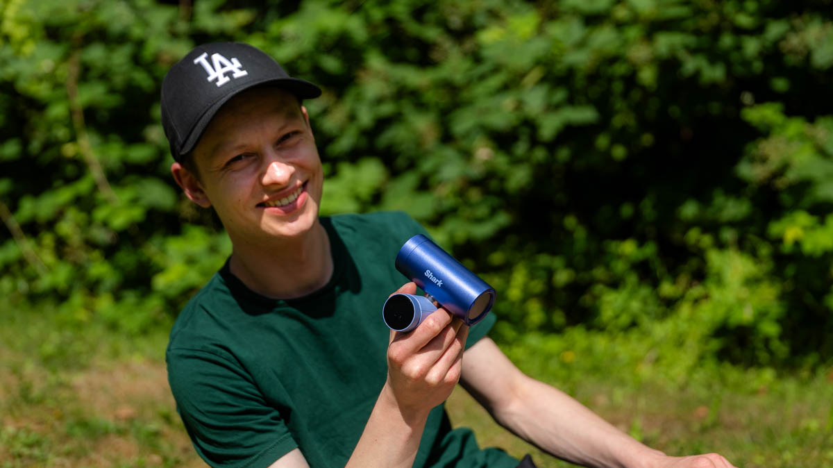 Alex bläst sich mit dem Handventilator Shark ChillPill Wind ins Gesicht.
