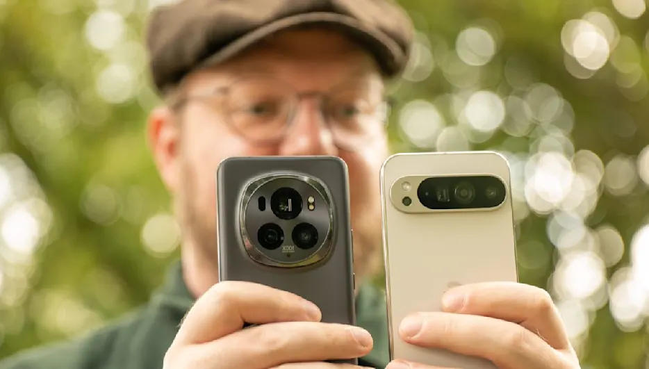 Eine Person hält zwei Mobiltelefone mit Kameras in der Hand, der Hintergrund ist unscharf.