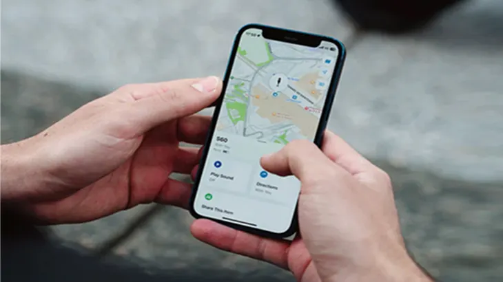 Eine Person hält ein Smartphone mit einer Karten-App in der Hand. Die Karte zeigt eine grüne und weiße Landschaft.