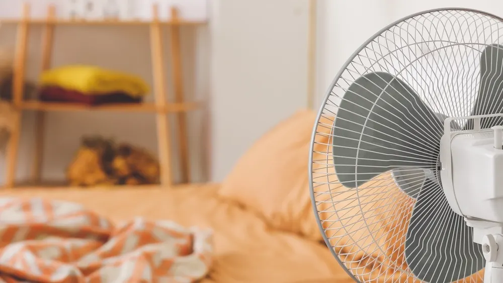 Ein Ventilator ist auf ein Bett gerichtet.
