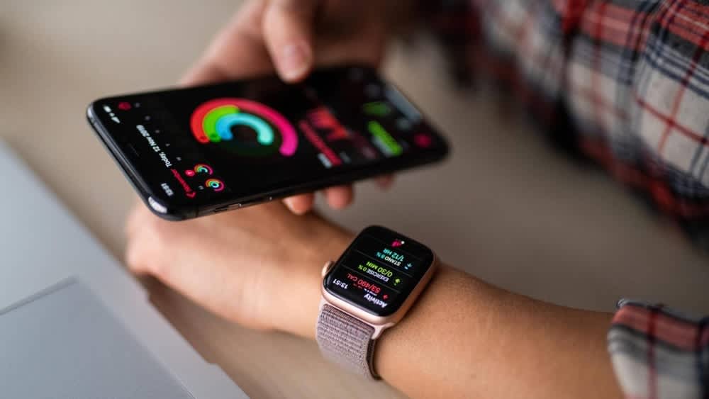 Ein Handy und eine Smartwatch an einem Arm, jeweils lädt ein Update auf dem Display