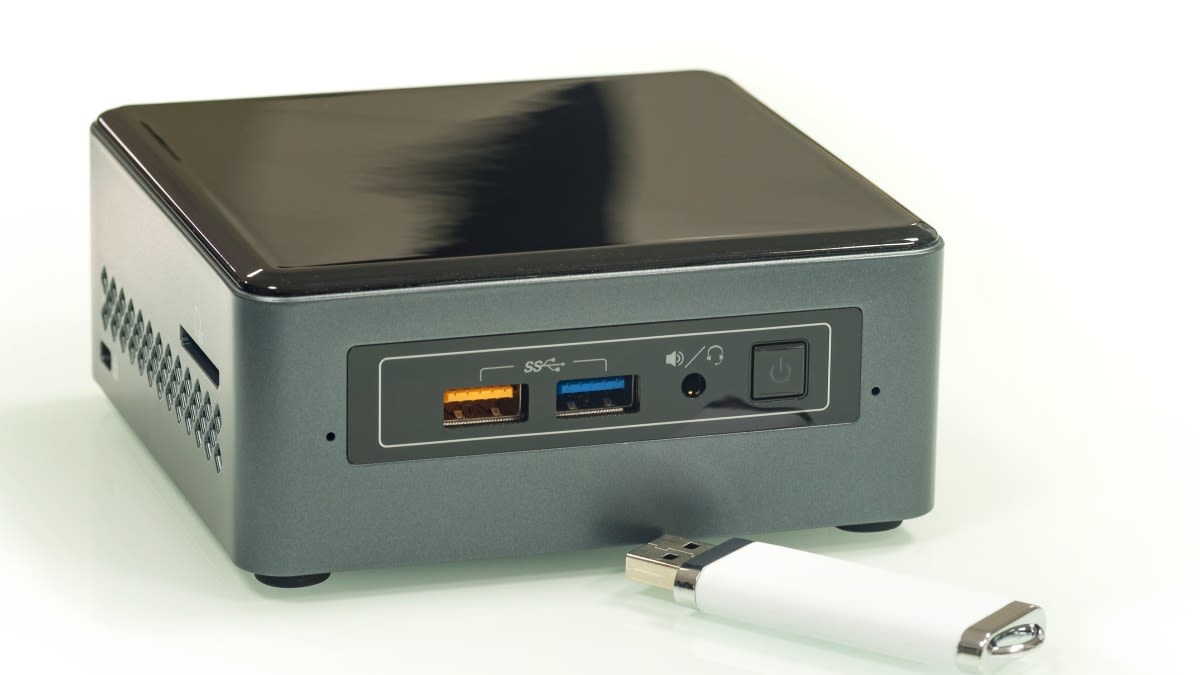 Ein Mini-PC mit USB-Stick vor weißem Hintergrund.