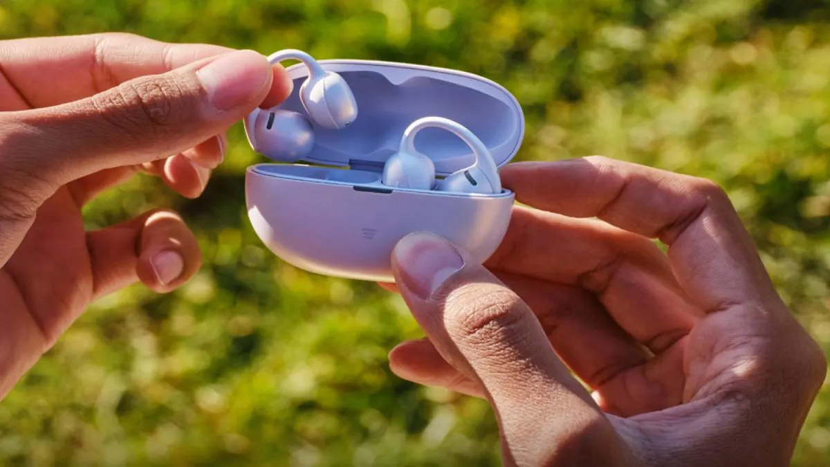 Zwei Hände halten das Ladecase der Open-Ear-Kopfhörer Shokz OpenDots Air und entnehmen einen der beiden Earbuds.