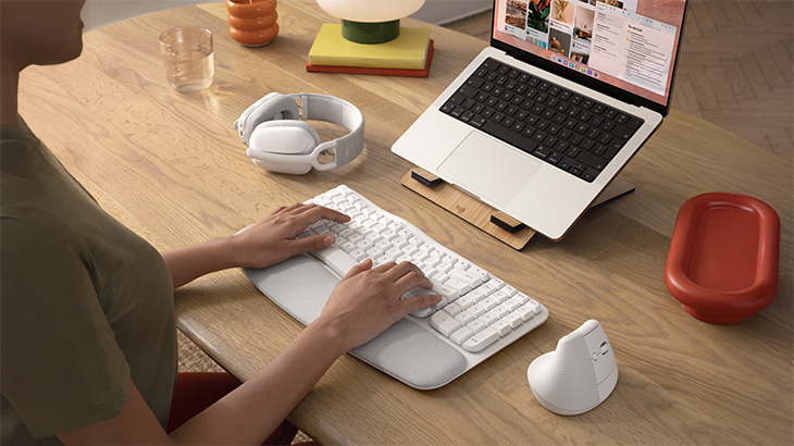 Moderner Arbeitsplatz mit ergonomischer Tastatur, vertikaler Maus und Headset. Die Anordnung der Geräte unterstützt komfortables und produktives Arbeiten am Computer.