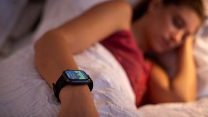 eine_junge_frau_schlaeft_im_bett_mit_einem_schlaftracker