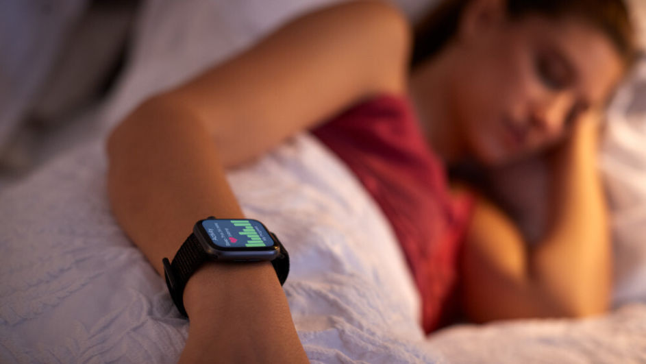 Junge Frau schläft im Bett mit Smartwatch Schlaftracker