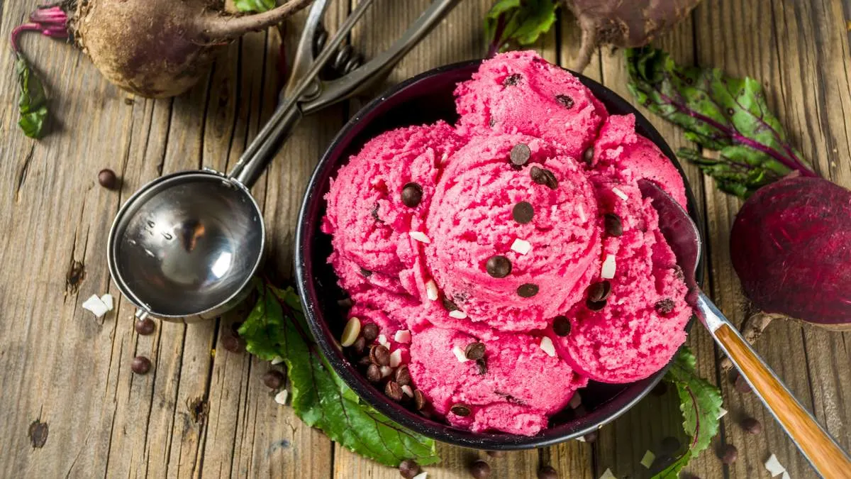 Mehrere Kugeln Rote-Bete-Eis sind mit Schokostückchen in einer Schüssel angerichtet.