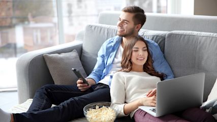 junges Paar liegt auf dem Sofa und schaut fernsehen