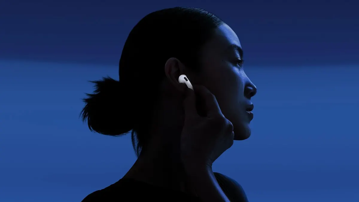 Eine Frau berührt einen AirPod 4 in ihrem rechten Ohr.