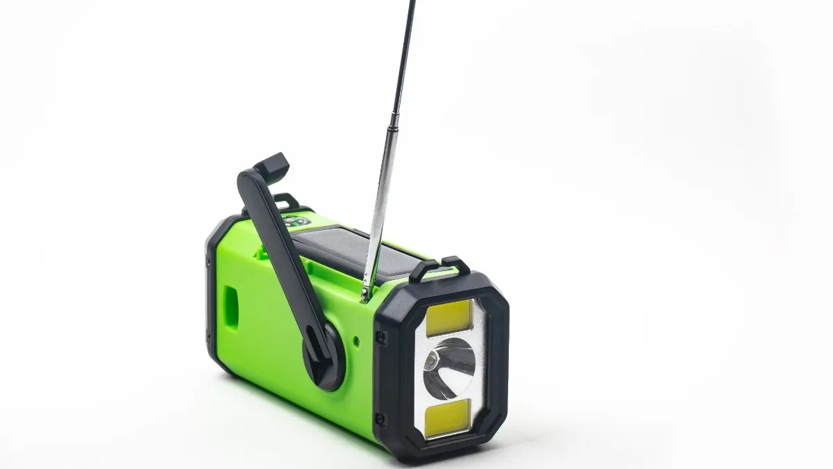 Ein neongrünes Kurbelradio mit ausgefahrener Antenne vor weißem Hintergrund.