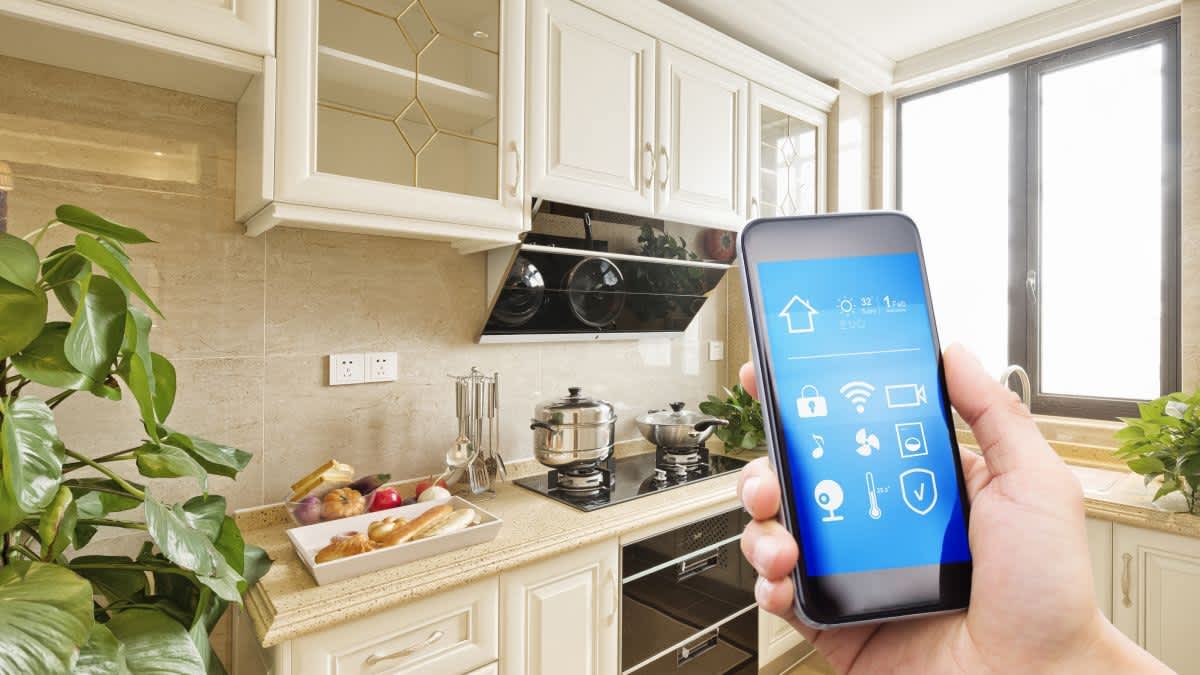 Eine Smart-Home-Küche wird mit einem Smartphone gesteuert.