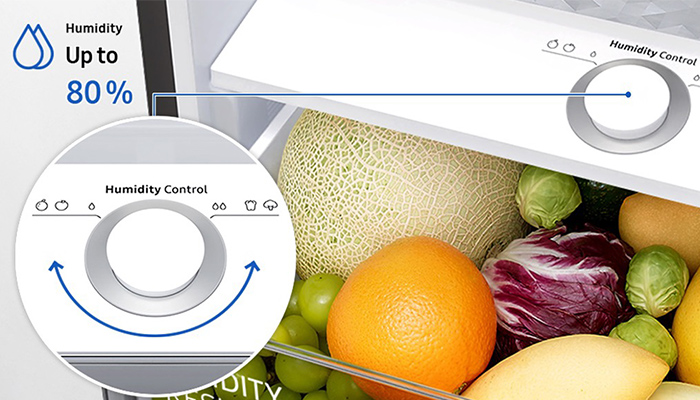 Ein Kühlschrankfach mit einem Feuchtigkeitsregler, gefüllt mit einer Honigmelone, Orange, Trauben, Rosenkohl und Radicchio.