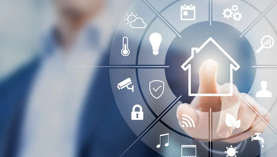 Ein Finger berührt ein Haus-Symbol auf einer runden Oberfläche mit Icons für Wetter, Sicherheit und Medien. Eine Person im Anzug ist unscharf.
