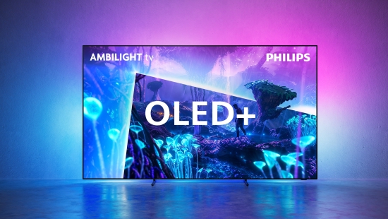 Ein schwarzer OLED+ Fernseher zeigt eine Bühne mit blauen und pinken Lichtern. Weiße Buchstaben stehen im Vordergrund. Der Hintergrund ist pink und blau.