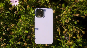 Nachhaltige ISY Handyhülle für das iPhone14 liegt im Gras. Die Farbe der Hülle ist lila.