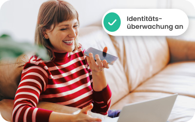 Frau im rot-weiß gestreiften Oberteil sitzt auf einem Sofa, hält ein Handy und arbeitet an einem Laptop. Eine Sprechblase mit grünem Haken und Text.