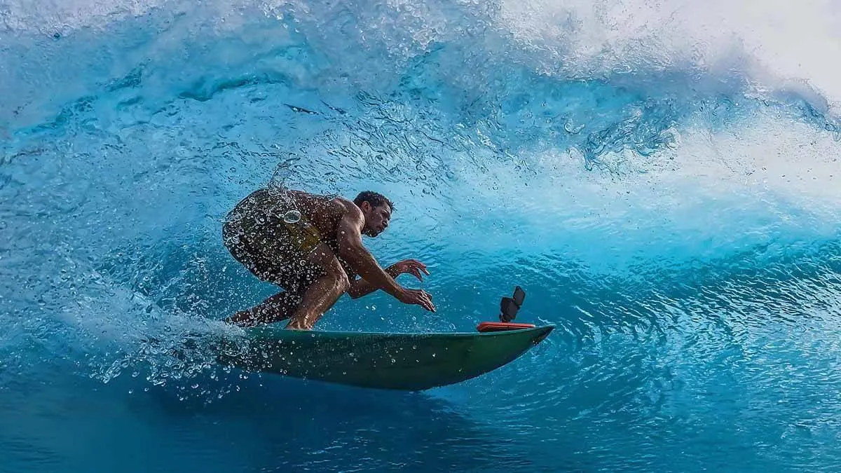 Ein Mann beim Surfen, die Action-Cam Insta360 Ace Pro 2 ist vorn auf dem Surfboard angebracht.