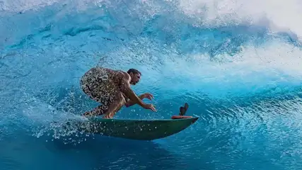 Ein Mann beim Surfen, die Action-Cam Insta360 Ace Pro 2 ist vorn auf dem Surfboard angebracht.