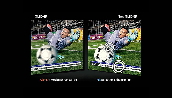 Ein Torwart in grauer Uniform fängt einen Fußball vor einem Tor auf einem grünen Rasen. Zwei Bildschirme zeigen die Szene.