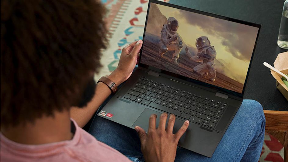 Eine Person sitzt mit einem offenem Laptop auf ihrem Schoß.
